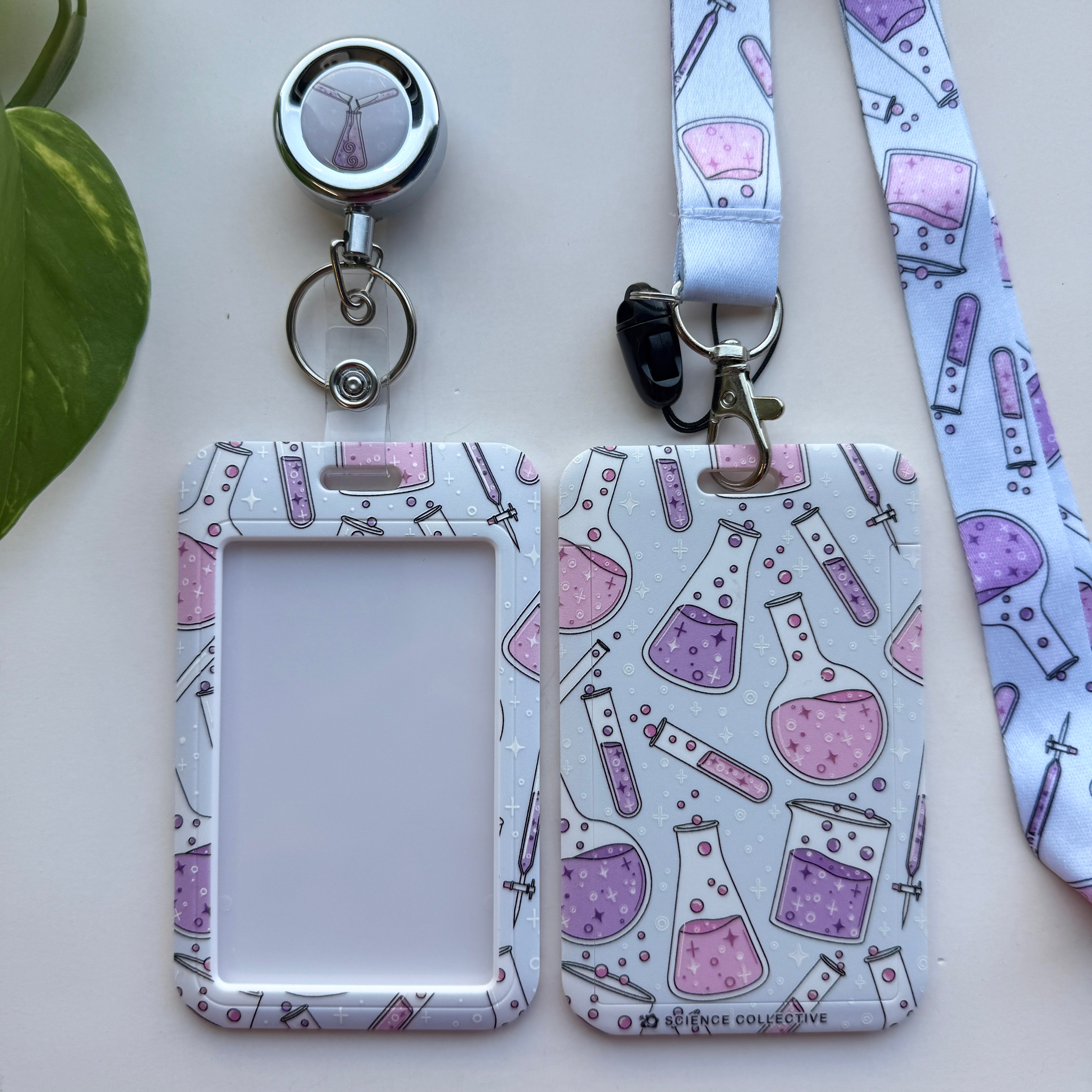 Chemistry lanyard, badge holder, and retractable badge reel featuring a pattern of whimsical pink and purple chemistry flasks and tubes.